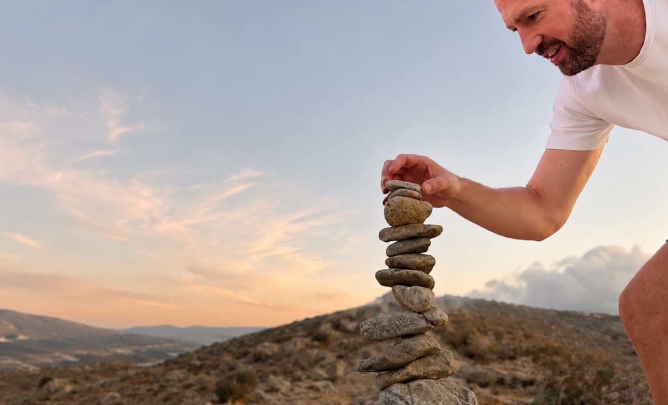 Roy van Sichem, founder of Awaren and mindfulness trainer, stacking stones at sunset